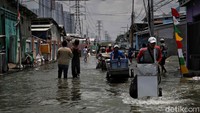 Meski air merendam jalan, para pedagang tetap mendorong gerobak mereka dan menjajakan beragam produk dagangan mereka demi memenuhi kebutuhan hidup sehari-hari.