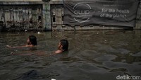Jalan-jalan yang terendam banjir tersebut pun menjadi kolam renang dadakan bagi anak-anak di kawasan itu.