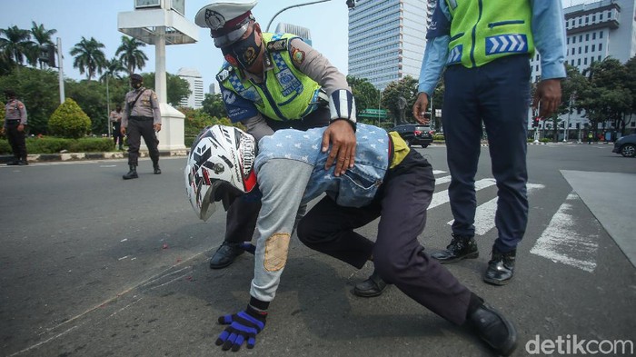 Seorang pengendara motor tergeletak di kawasan Patung Kuda, Jakarta, Selasa (17/11/2020). Usai kecelakaan sejumlah petugas membantu korban.