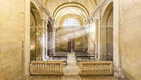 Gereja Abad ke-12, 16, dan ke-20, di Italia. Cahaya masuk di celah celah jendela menyinari dalam gereja yang terdapat susunan kursi-kursi.  