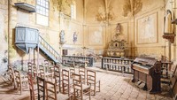 Gereja Abad 13, 14, 16, dan 19, Prancis, Wilayah Nouvelle-Aquitaine. Segalanya tampak masih teratur dengan sempurna. Kursi kayu masih berjejer, batu paving merah muda yang berdebu, alat musik masih berdiri.  