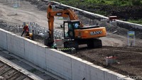 Alat berat terus bekerja meratakan tanah untuk jalur kereta cepat. Sementara sejumlah pekerja sibuk membangun dinding beton di kedua sisi jalur.