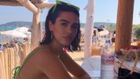 Pantai menjadi salah satu tempat favorit Amelia. Pemilik bibir tebal ini pun pilih menyegarkan diri dengan sebotol air mineral. Foto: Instagram ameliagray
