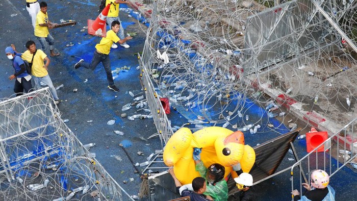 Pro-democracy protesters take cover with inflatable ducks as police fire water cannons during an anti-government rally near the Parliament in Bangkok, Tuesday, Nov. 17, 2020. Thailands political battleground shifted to the countrys Parliament Tuesday, where lawmakers are considering proposals to amend the countrys constitution, one of the core demands of the student-led pro-democracy movement. (AP Photo/Wason Wanichakorn)
