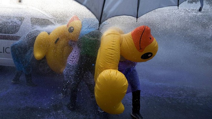 Bebek Karet Jadi Tameng Pendemo di Thailand Pro-democracy protesters take cover with inflatable ducks as police fire water cannons during an anti-government rally near the Parliament in Bangkok, Tuesday, Nov. 17, 2020. Thailand's political battleground shifted to the country's Parliament Tuesday, where lawmakers are considering proposals to amend the country's constitution, one of the core demands of the student-led pro-democracy movement. (AP Photo/Wason Wanichakorn)