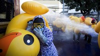 Tampak para pengunjuk rasa mengenakan jas hujan lengkap dengan kacamata pelindung dan masker membawa bebek karet sebagai tameng mereka dari semburan air.  