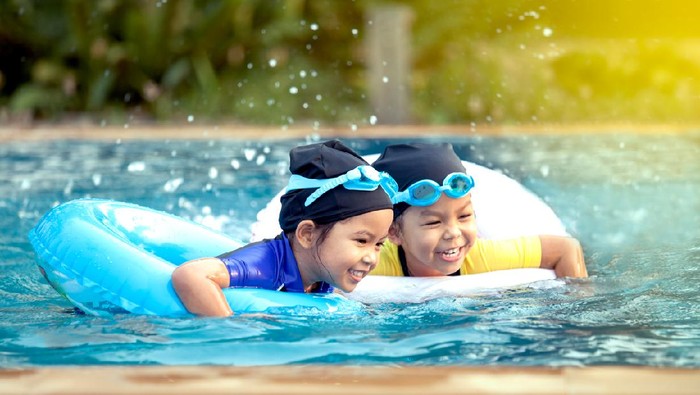 berenang two asian little girls having fun to swim in swimming pool together