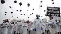 Petugas medis dengan mengenakan masker melepas puluhan balon udara berwarna hitam di Bucharest, Rumania, Selasa, 17 November 2020 waktu setempat.