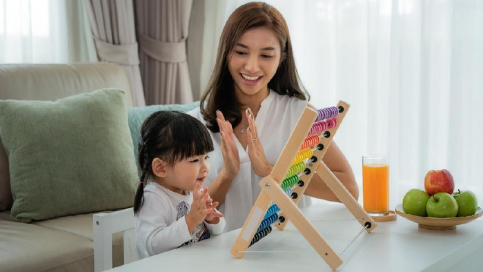 Happy Asian young mother and daughter playing with abacus, early education at home.