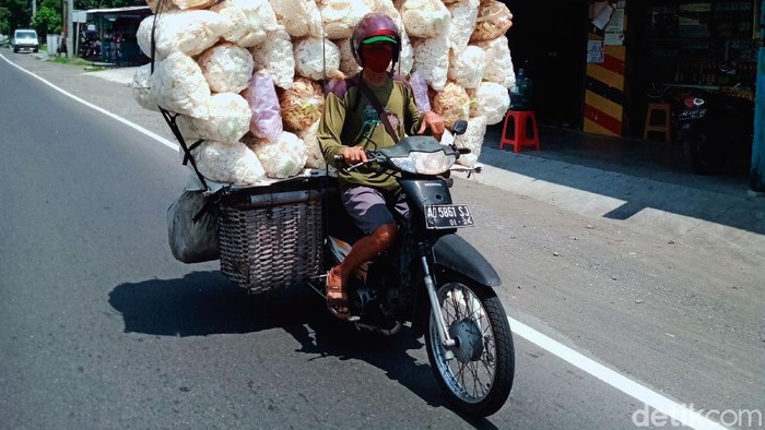 Seorang pedagang yang mengangkut 43 kemasan kerupuk menggunakan sepeda motor melintas di Jalan Yogya-Solo. Meski bahaya, pedagang itu tetap santai melintas di jalan raya.