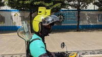 Seorang driver ojek online yang memakai helm unik melintas di Jalan Thamrin, Jakarta.