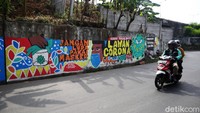 Pengendara melintas di depan mural bertema COVID-19 di Jalan Cakung Cilincing Barat, Jakarta Timur, Kamis (19/11/2020). 