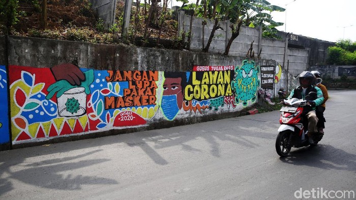 Pengendara melintasi mural bertema COVID 19 di Jalan Cakung Cilincing Barat, Jakarta Timur, Kamis (19/11/2020). Mural masih dianggap menjadi sarana edukasi kesehatan yang tepat bagi warga untuk menjaga diri dari penularan virus Covid 19.