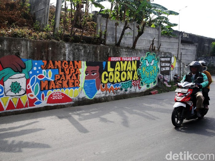 Pengendara melintasi mural bertema COVID 19 di Jalan Cakung Cilincing Barat, Jakarta Timur, Kamis (19/11/2020). Mural masih dianggap menjadi sarana edukasi kesehatan yang tepat bagi warga untuk menjaga diri dari penularan virus Covid 19.