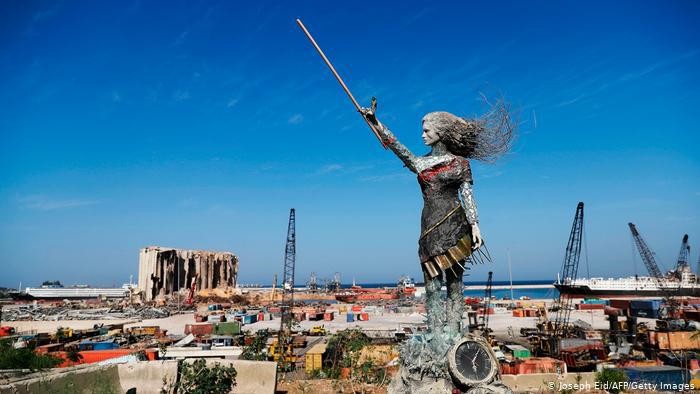 Patung karya Hayat Nazer, yang dibuat dari puing-puing ledakan di pelabuhan Beirut, seperti tampak di latar belakang.