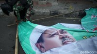 Seorang prajurit TNI melepas spanduk dari tiang penyangganya.