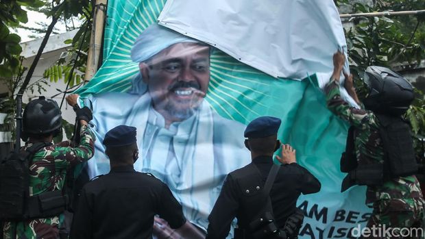 Sejumlah personel TNI menurunkan spanduk besar bergambarkan Habib Rizieq di Jakarta, Jumat (20/11/2020). Mereka turut membawa panser saat beraksi.