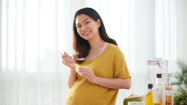 Young beautiful pregnant woman preparing healthy meal with fruites and vegetables
