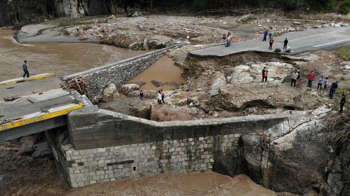 Jembatan Hancur Terdampak Badai Iota di Honduras COPAN, HONDURAS - NOVEMBER 19: Men look at the road washed out by the Higuito river and the destroyed bridge as people try to walk across on November 19, 2020 in Copan, Honduras. After hitting Colombian Islands of Providencia and San Andres, Hurricane Iota made landfall in Haulover, Nicaragua, on Monday night as a category 4 storm causing landslides, floods and destroying trees and houses. (Photo by Yoseph Amaya/Getty Images)