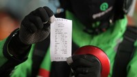 Seorang driver Ojol menunjukan hasil uji emisi sepeda motornya.