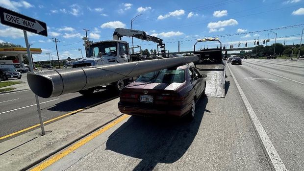 In this photo provided by the Florida Highway Patrol a downed power pole is strapped to the roof of a car, Monday, Nov. 16, 2020, on Interstate 4, in Hillsborough County, Fla. A state trooper pulled over a maroon Toyota Camry with a metal light pole, longer than the car itself, strapped to the roof on a Tampa road Monday morning, according to a Florida Highway Patrol report. The Camry's driver, Douglas Allen Hatley, told troopers that he had found the pole on the ground by the side of the highway and had planned to sell the metal for scrap, according to the report.   Hatley charged with grand theft was being held on $2,000 bond. (Florida Highway Patrol via AP)
