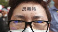 Penampakan seorang demonstran yang di bagian dahinya terlihat bertuliskan  Anti babi beracun saat ikut serta dalam aksi unjuk rasa menuntut pembatalan keputusan mengizinkan impor daging babi AS ke Taiwan.