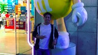 Siapa tak kenal maskot ini? Enea tak melewatkan foto di depan maskot permen cokelat M&M’s berwarna kuning. Foto: Instagram eneabastianini