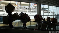 Para penumpang yang membawa barang bawaan berupa kardus hingga tas besar menaiki KM Dorolonda.