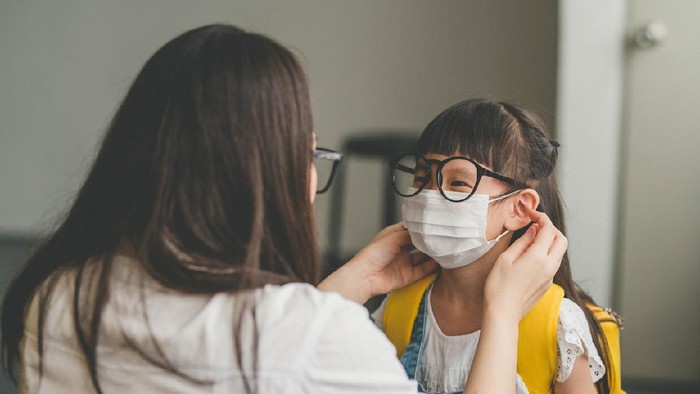 Anak pakai masker Image of Asian mother help her daughter wearing medical mask to prepare go to school. Avoiding Covid-19 or coronavirus outbreak.