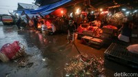 Seorang warga membersihkan sampah yang yang tergenang di Pasar Induk Cibitung akibat hujan mengguyur kawasan tersebut.