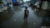 Seorang warga membawa payung saat beraktivitas di kawasan Pasar Induk Cibitung yang becek akibat diguyur hujan.