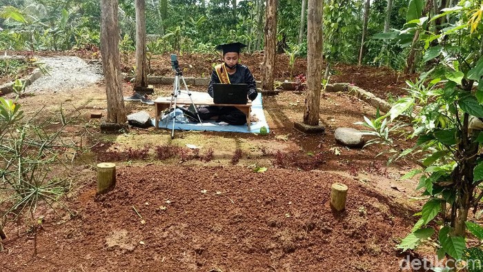 Mochamad Nadif Nasrulloh (23) mengikuti wisuda virtual di depan makam bapaknya, Desa Sidarata, Banjarnegara, Selasa (24/11/2020)