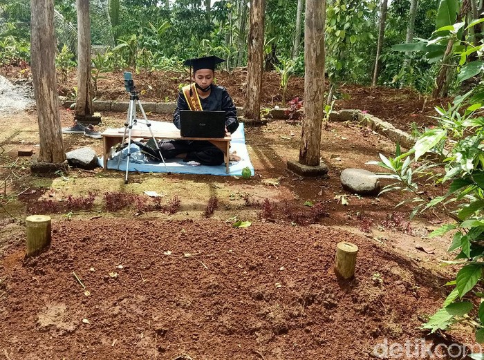 Mochamad Nadif Nasrulloh (23) mengikuti wisuda virtual di depan makam bapaknya, Desa Sidarata, Banjarnegara, Selasa (24/11/2020)