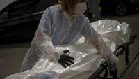 Seorang petugas menutupi tubuh jenazah pasien COVID-19 dengan plastik guna mencegah penyebaran virus Corona.
