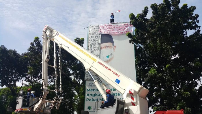 Seorang pria memanjat tiang reklame di lapangan Mabes Polri.