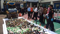 Ratusan botol minuman keras dan ratusan botol liquid vape dimusnahkan dengan cara digilas alat berat.