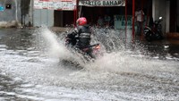 Pengendara sepeda motor nekat menerobos banjir.