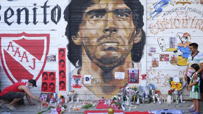 BUENOS AIRES, ARGENTINA - NOVEMBER 25: A fan mourning Diego Maradona places a picture in an altar outside Argentinos Juniors Diego Maradona Stadium on November 25, 2020 in Buenos Aires, Argentina. Diego Maradona, considered one of the biggest football stars in history, died at 60 from a heart attack on Wednesday in Buenos Aires. (Photo by Fernando de Dios/Getty Images)