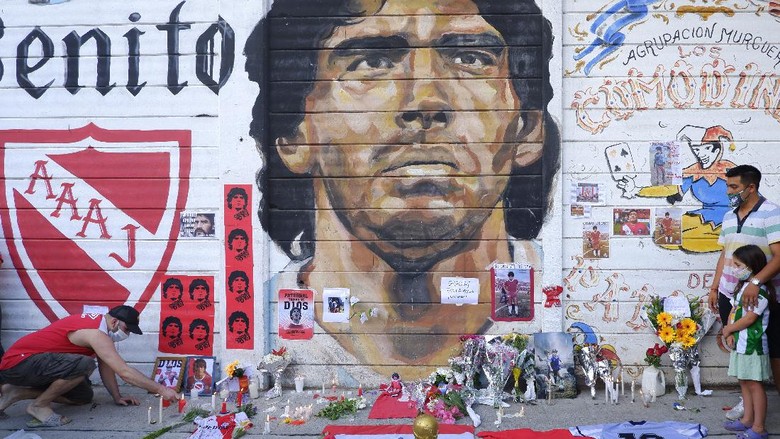 Diego Maradona BUENOS AIRES, ARGENTINA - NOVEMBER 25: A fan mourning Diego Maradona places a picture in an altar outside Argentinos Juniors Diego Maradona Stadium on November 25, 2020 in Buenos Aires, Argentina. Diego Maradona, considered one of the biggest football stars in history, died at 60 from a heart attack on Wednesday in Buenos Aires. (Photo by Fernando de Dios/Getty Images)