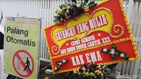 Dari sekian banyak karangan bunga, nampak satu karangan bunga yang menarik perhatian karena tulisan di karangan bunga tersebut. Karangan bunga bertuliskan SAYANGKU YANG MULIA. CEPAT SEMBUH. AKU RINDU DUDUK CANTIK XXX.