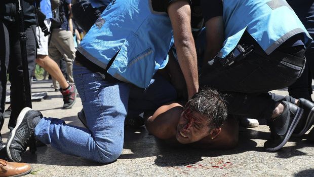 Police detain a soccer fan at Plaza de Mayo, where mourners are lining up to see the casket with the remains of Diego Maradona lying in state inside the presidential palace, in Buenos Aires, Argentina, Thursday, Nov. 26, 2020. The Argentine soccer great who was among the best players ever and who led his country to the 1986 World Cup title died from a heart attack at his home Wednesday, at the age of 60. (AP Photo/Rodrigo Abd)