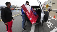 Seorang karyawan membantu memasukan TV 65 inci ke dalam mobil seorang pembeli di Wilkes-Barre. Mark Moran/The Citizens Voice via AP.