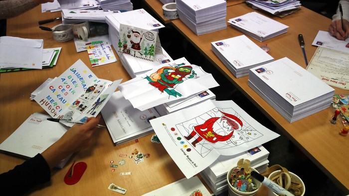 Potret Puluhan Ribu Surat Natal dari Anak-anak Prancis A postal worker shows an envelope from Jim of Taiwan, who sent a face mask inside the letter he sent and wrote
