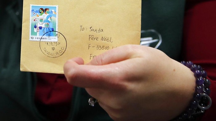 Potret Puluhan Ribu Surat Natal dari Anak-anak Prancis A postal worker shows an envelope from Jim of Taiwan, who sent a face mask inside the letter he sent and wrote