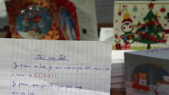 Potret Puluhan Ribu Surat Natal dari Anak-anak Prancis A postal worker shows an envelope from Jim of Taiwan, who sent a face mask inside the letter he sent and wrote