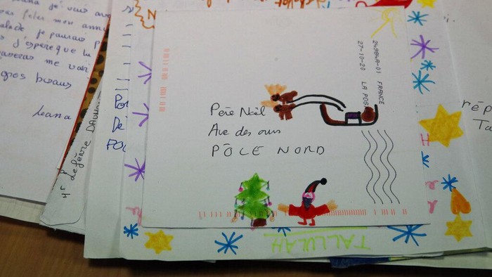 Potret Puluhan Ribu Surat Natal dari Anak-anak Prancis A postal worker shows an envelope from Jim of Taiwan, who sent a face mask inside the letter he sent and wrote
