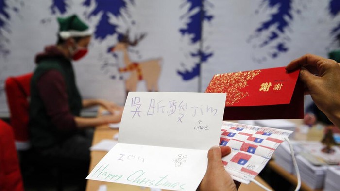 Potret Puluhan Ribu Surat Natal dari Anak-anak Prancis A postal worker shows an envelope from Jim of Taiwan, who sent a face mask inside the letter he sent and wrote
