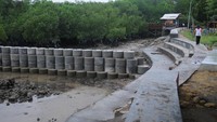 Warga berjalan di dekat tangkis laut (tanggul penahan ombak) yang baru selesai dibangun di kawasan Pantai Wisata Talang Siring, Pamekasan, Jawa Timur, Sabtu (28/11/2020).
