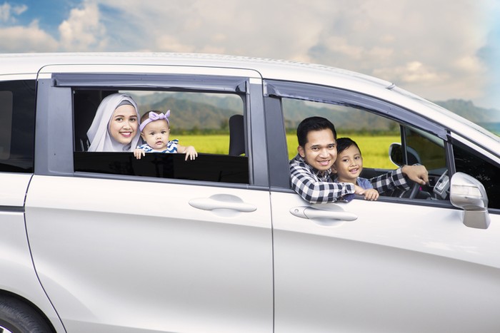 Portrait of Muslim family looking out of a car window while driving for travel on vacation