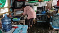 Seorang pedagang tetap beraktivitas di tengah banjir rob.